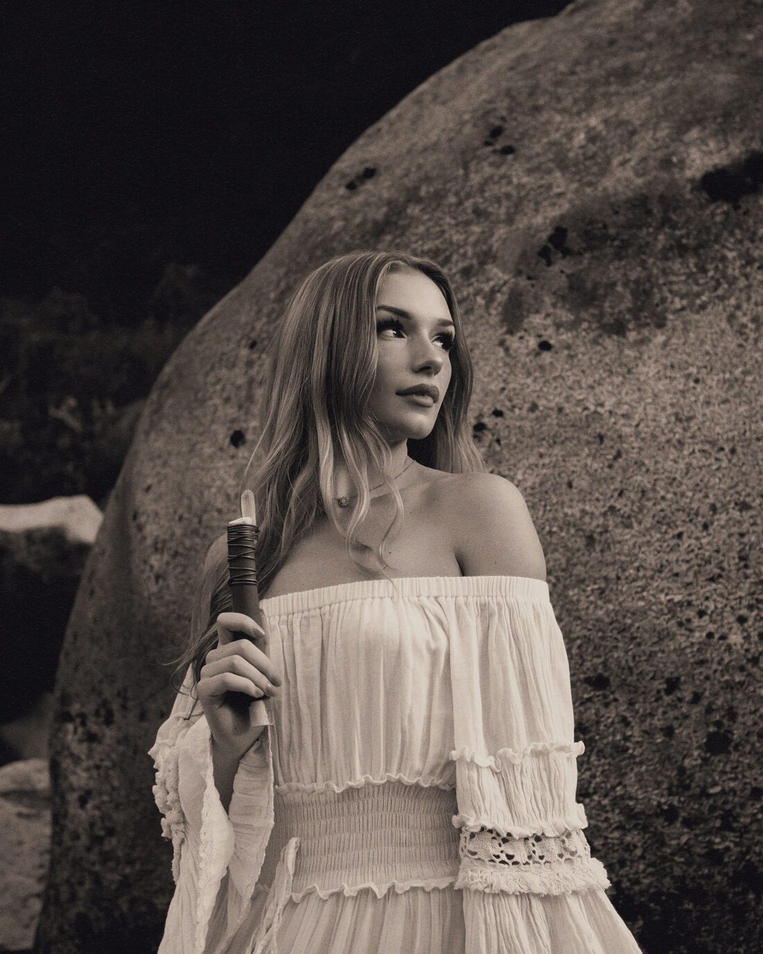 Izzy holding a ritual blade beside a granite boulder