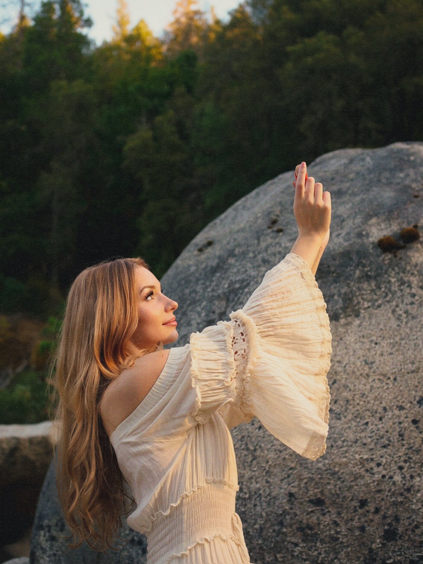 Izzy in a cream dress, hand lifted toward the light