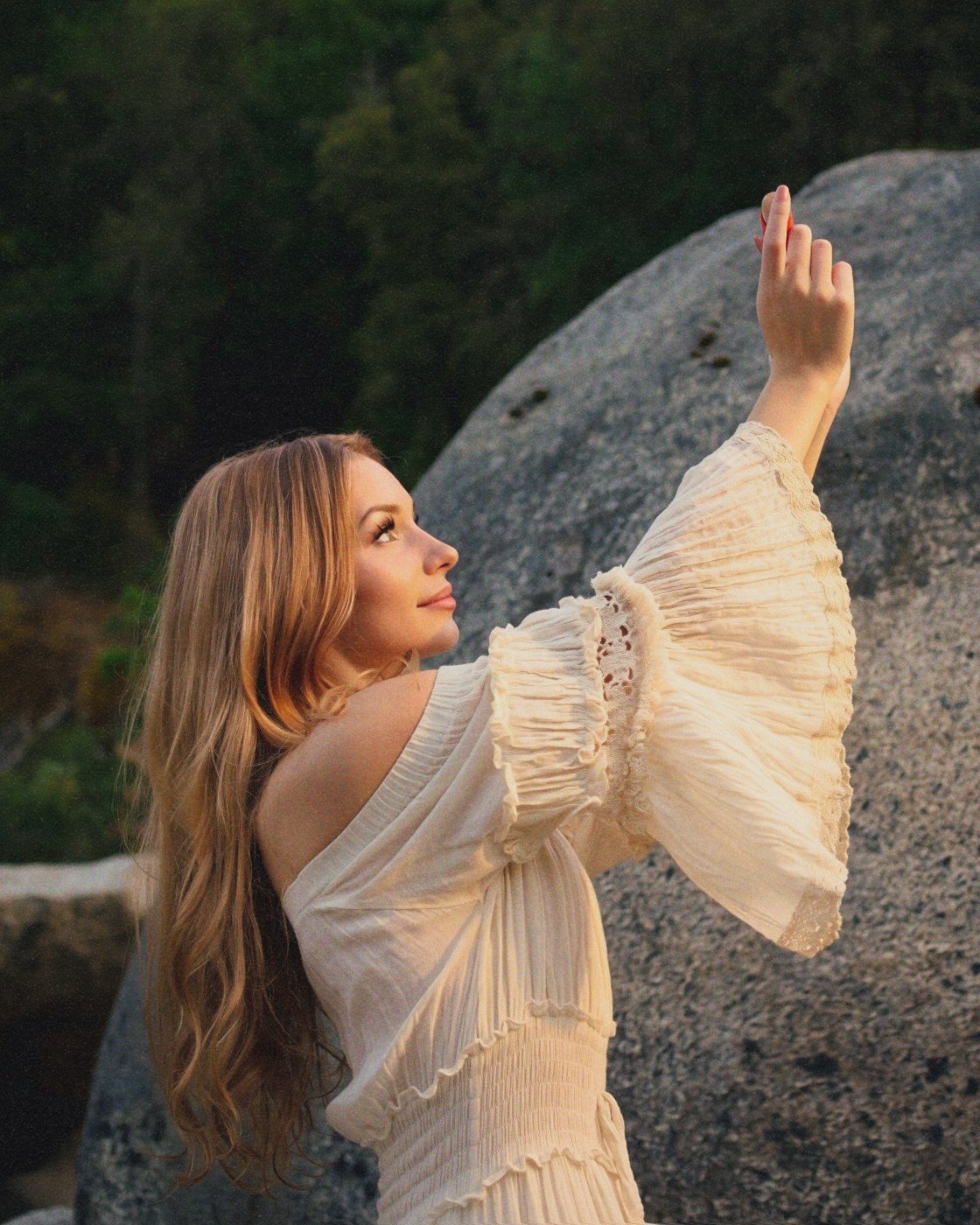 Izzy in a cream dress, hand lifted toward the light